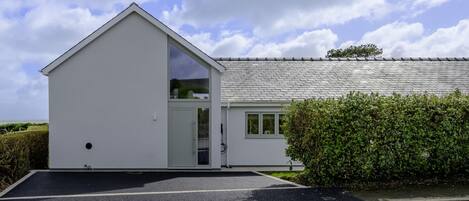 A modern single-story building with a sloped roof, a large window, and a door.