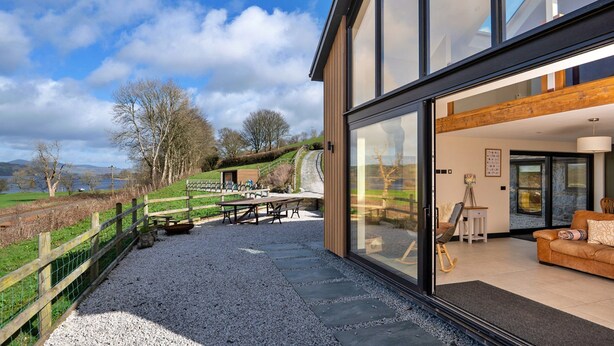 A modern house with a patio, a dining area, and a view of the countryside. - Luxury Lodge With Swim Spa for 8 (Bala)
