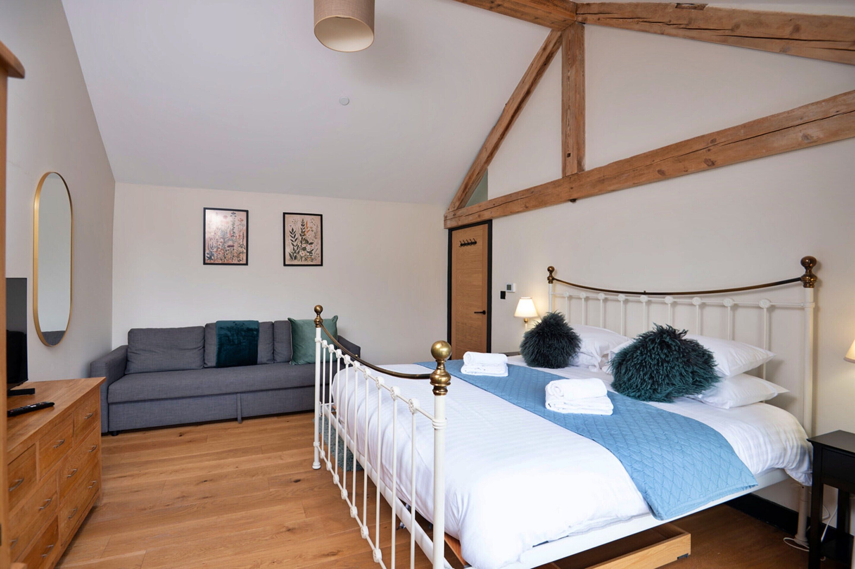 A bedroom with a bed, a sofa, a dresser, and a mirror.