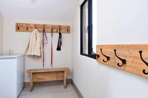 Une petite pièce propre, avec un banc en bois, un porte-manteau et une fenêtre.