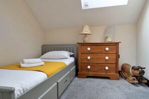 Ein Schlafzimmer mit einem Bett, einem Schminktisch, einer Lampe und einem Spiegel.