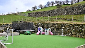 A playground with artificial turf, a slide, and a climbing structure. - Luxury Lodge With Swim Spa for 8 (Bala)
