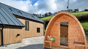 A modern building with a sloped roof and a wooden structure with a curved roof. - Luxury Lodge With Swim Spa for 8 (Bala)