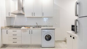 Une cuisine moderne avec des meubles blancs, une hotte en acier inoxydable, un lave-vaisselle encastré et un four à micro-ondes.