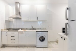 Een moderne keuken met witte kastjes, een roestvrijstalen afzuigkap, een inbouw vaatwasser en een magnetron.