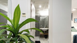 Une salle de bain moderne avec une douche, un lavabo et une plante en pot.