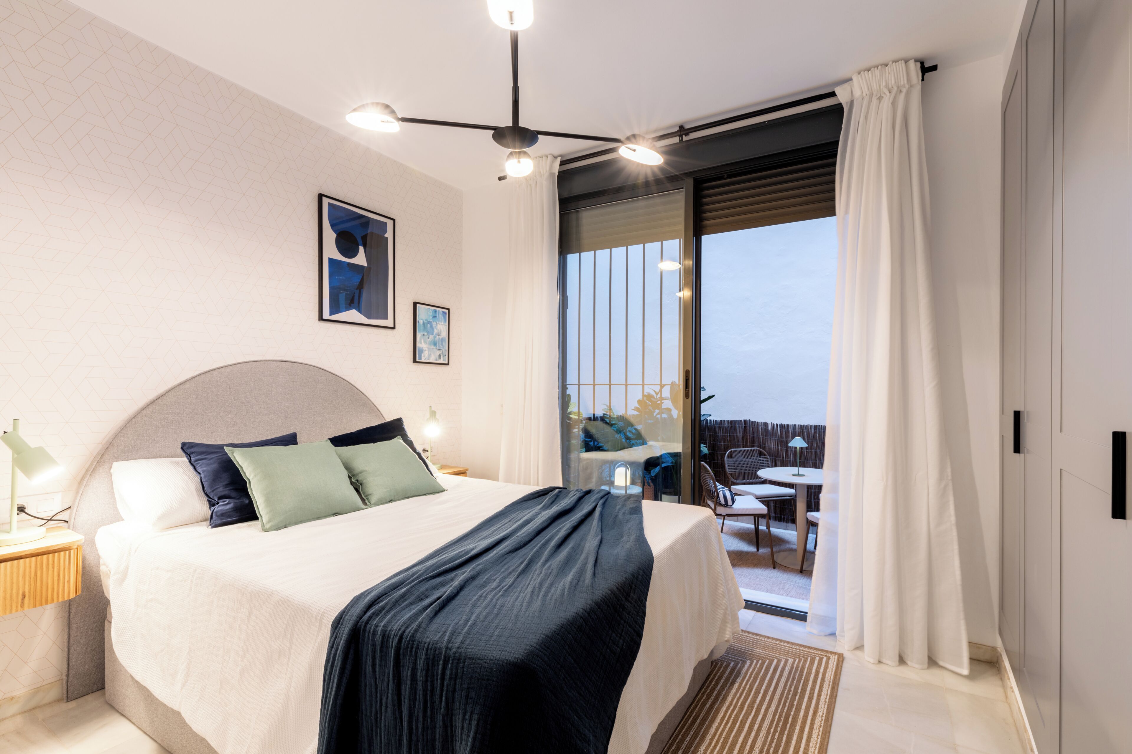 Une chambre moderne avec un grand lit, une table de chevet, un bureau et un balcon avec vue.