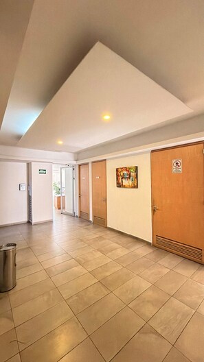 A hotel corridor with a tiled floor, wooden doors, and a painting on the wall. - One-of-a-Kind Venue: Akron World Stadium 2026 (Zapopan)