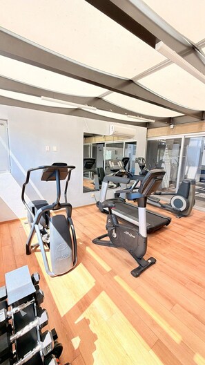 Une salle de sport équipée de tapis de course, de vélos d’appartement et d’appareils de musculation.