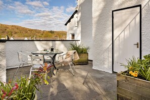 Eine Terrasse mit Tisch, Stühlen, einer Tür und Kübelpflanzen.