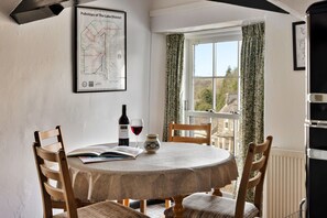 Comedor con una mesa redonda, sillas, una botella de vino y un mapa en la pared.