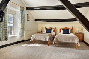 A bedroom with two single beds, a window with curtains, a radiator, and a wooden ceiling beam. - Charming Snowdonia Cottage for 4 (Ambleside)