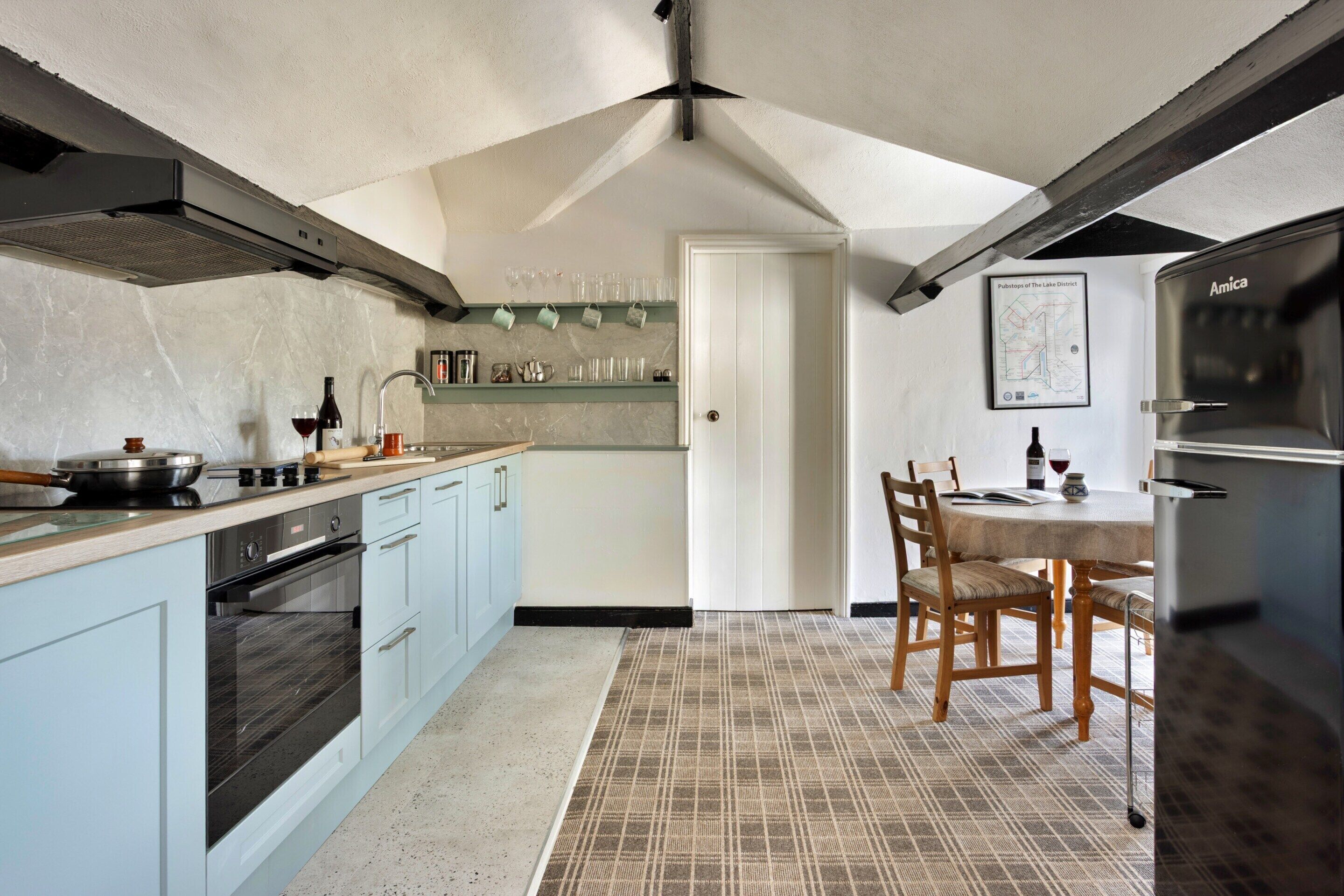 A kitchen with a central island, a dining table with chairs, and a refrigerator.