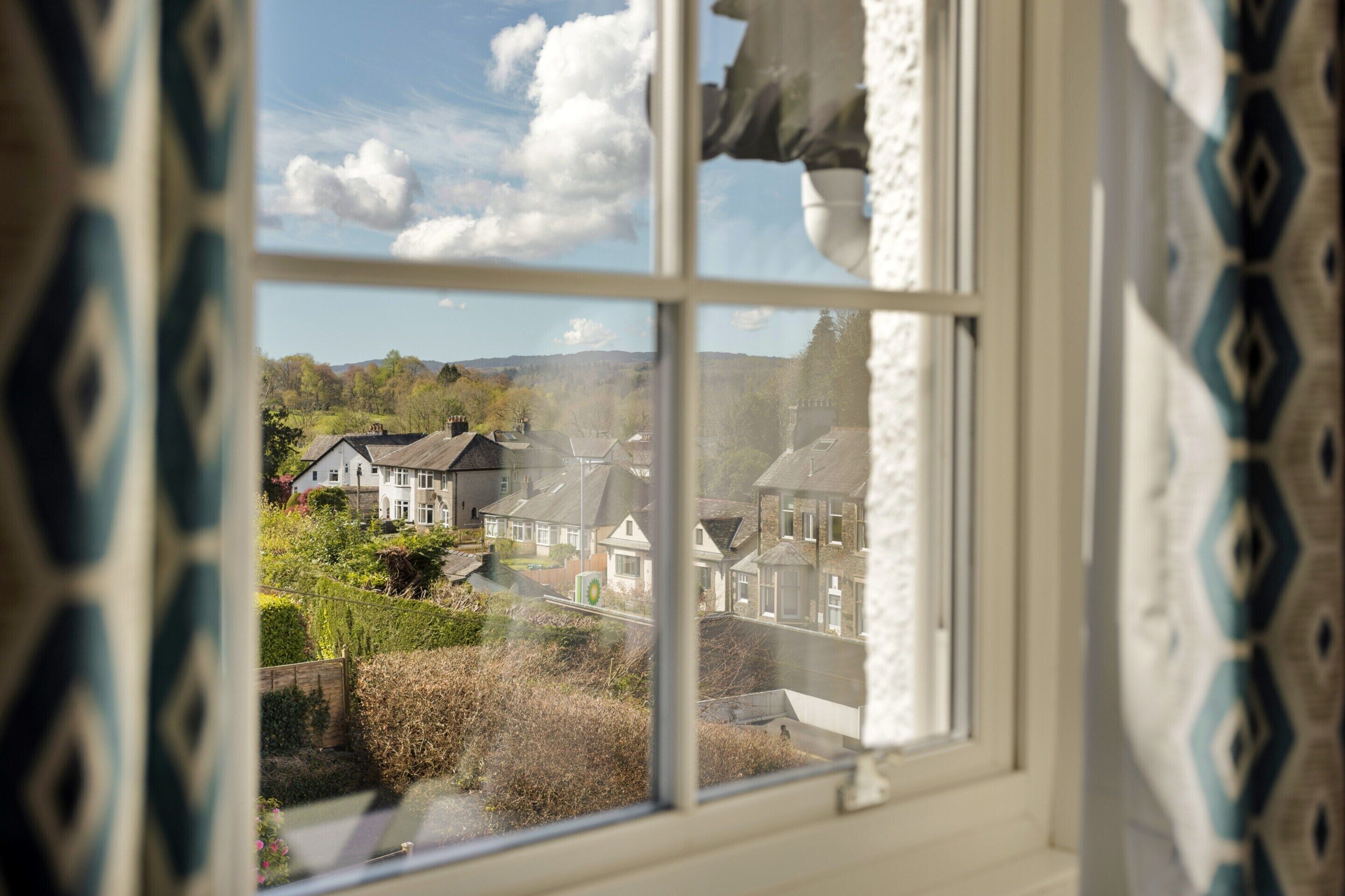 A window view of a residential area with houses and greenery.
