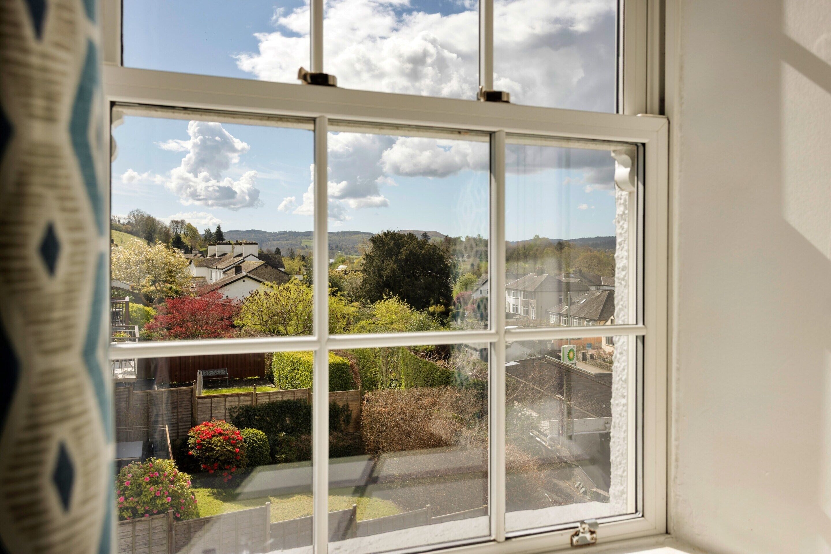 A window with a view of a residential area, including houses and greenery.