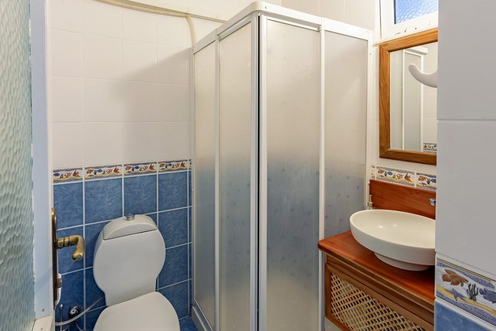 Casa de banho com sanita, lavatório e cabine de duche.