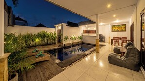 Ein moderner Außenbereich mit Swimmingpool, Essbereich und Küche.