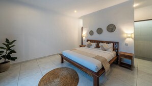 Ein Schlafzimmer mit einem Bett, Nachttischen, Wanddekoration und einer Topfpflanze.