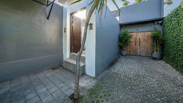 Ein Wohnhaus mit gepflastertem Innenhof, einer Holztür und einer kleinen Palme.