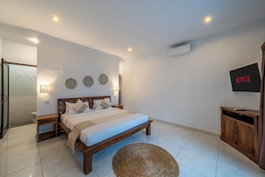 Une chambre à coucher comprenant un lit, des tables de chevet, un téléviseur et un climatiseur fixé au mur.