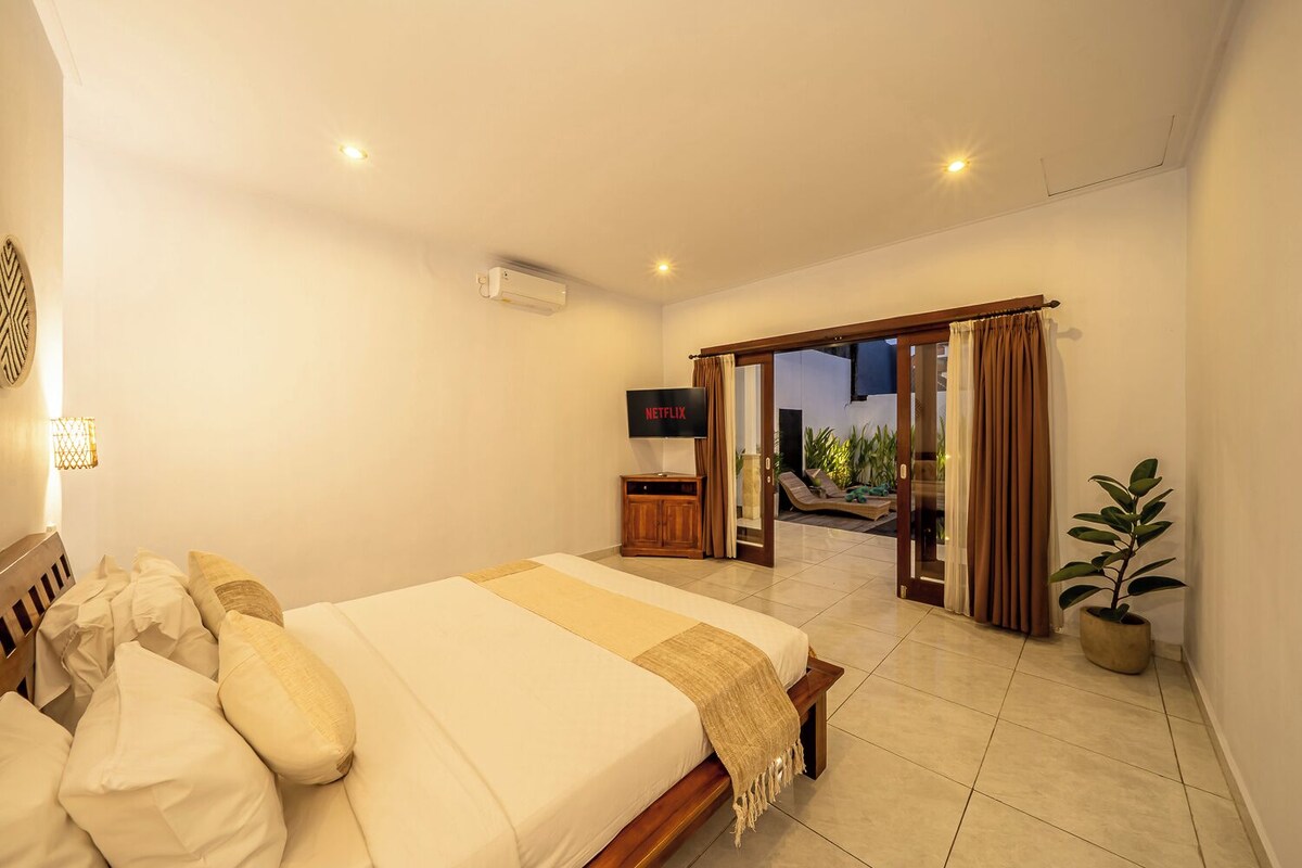 A bedroom with a bed, a TV, and a view of an outdoor area.