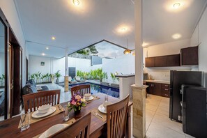 A modern kitchen with dark cabinets and a black refrigerator. - Villa Gede Seminyak (Badung)