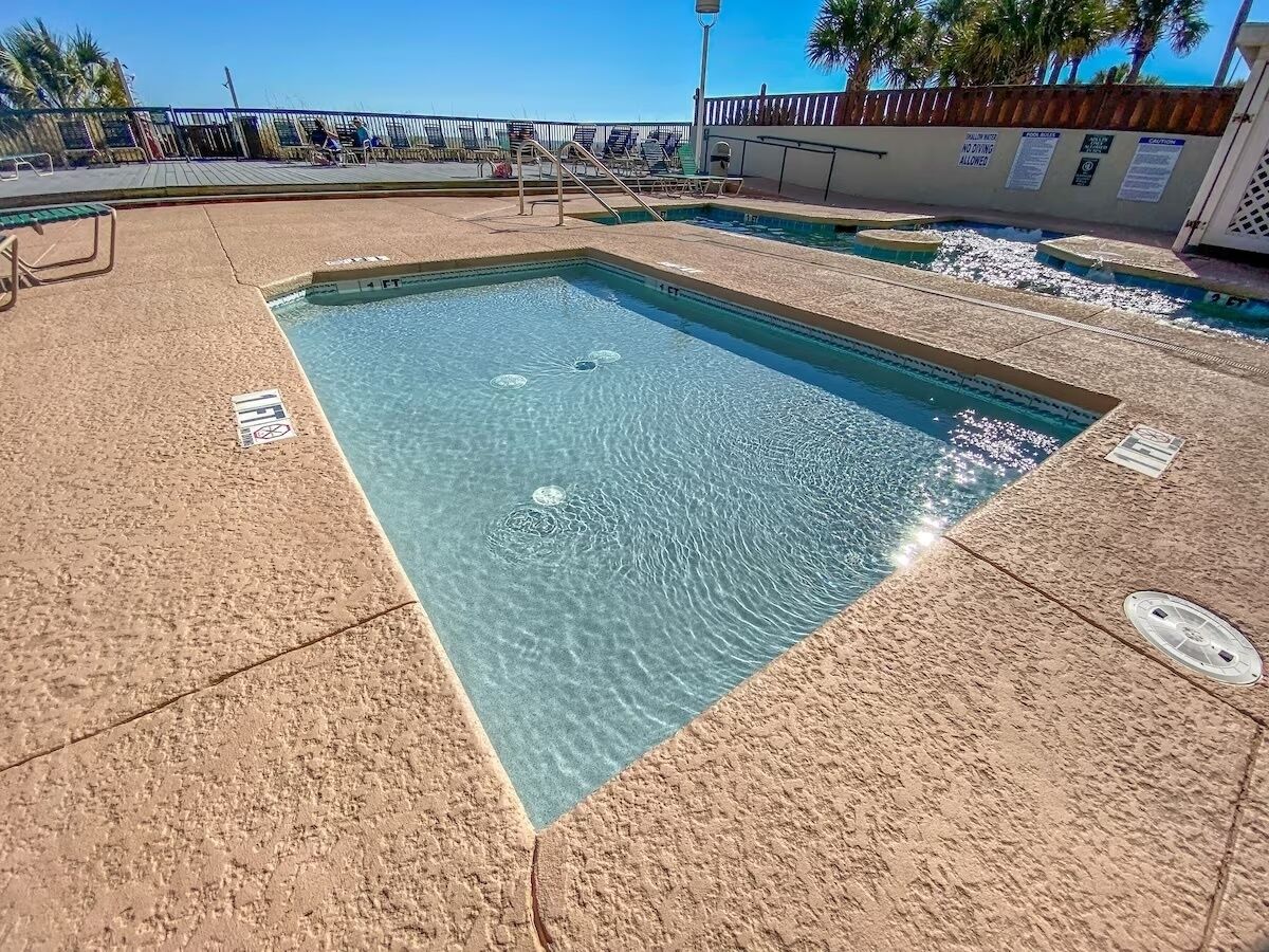 Ein rechteckiger Pool mit klarem Wasser, umgeben von einer strukturierten Poolterrasse.