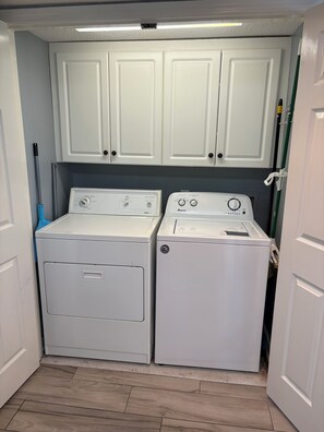 A laundry room with two white washing machines, a blue mop, and white cabinets. - Luxurious 4-Bedroom 4-Bathroom Condo North Myrtle Beach Oceanfront (North Myrtle Beach)