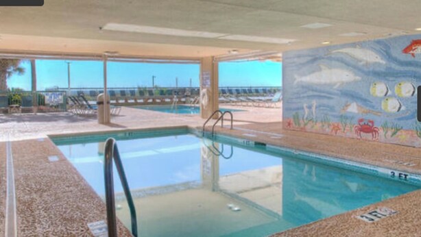 Una piscina interior con vistas despejadas a la playa y al océano.