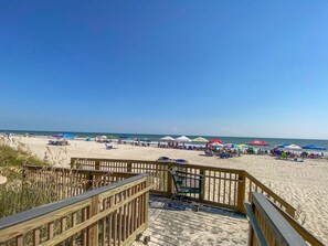 A beach with a wooden boardwalk leading to the shore, featuring a bench and a trash bin. - Luxurious 4-Bedroom 4-Bathroom Condo North Myrtle Beach Oceanfront (North Myrtle Beach)