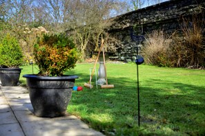 A garden with a stone wall, potted plants, and a croquet set. - Luxury Country Estate Near Largs (Betws-Y-Coed)