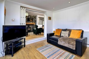 A modern living room with a flat-screen TV, a sofa with decorative pillows, a patterned rug, and a stone fireplace. - Luxury Country Estate Near Largs (Betws-Y-Coed)