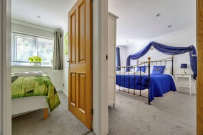 A bedroom with a bed, a window with curtains, a bedside table, and a nightstand. - Luxury Country Estate Near Largs (Betws-Y-Coed)