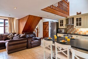 Cocina moderna con zona de comedor, que incluye una escalera de madera, un sofá y un espacio para desayunar.
