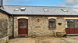 A stone building with a wooden door and windows, a sign reading 'GOOSE COTTAGE', and a wooden bench outside. - Luxury Whitby Townhouse for 10 (Bude)