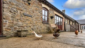A stone building with a sign reading 'GOOSE COTTAGE' and a wooden bench. - Luxury Whitby Townhouse for 10 (Bude)