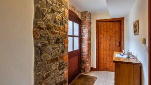 A hallway with a stone wall, a wooden door, and a wooden bench with a vase. - Luxury Whitby Townhouse for 10 (Bude)