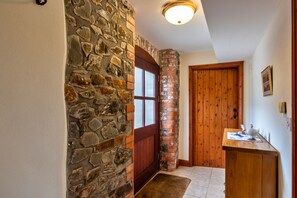 Ein Korridor mit einer Steinwand, einer Holztür und einer Holzbank mit einer Vase.