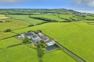 Vista aérea de una propiedad rural con un extenso campo, una piscina y un conjunto de edificios.