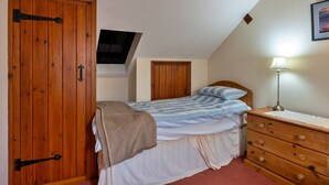 A bedroom with a bed, a dresser, a television mounted on the wall, and a wooden wardrobe. - Luxury Whitby Townhouse for 10 (Bude)