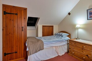 Ein Schlafzimmer mit einem Bett, einem Schminktisch, einem an der Wand montierten Fernseher und einem Holzschrank.