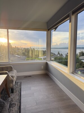 A corner room with a large window, a sofa, and a rug. - Spacious Sound View Top Floor Apartment with Large Deck (Federal Way)