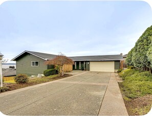 A two-story house with a garage, a driveway, and a well-maintained lawn. - Spacious Sound View Top Floor Apartment with Large Deck (Federal Way)