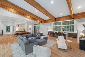 A spacious living area with a large gray sectional sofa, a white armchair, and a small round table. - Luxury Mountain Getaway Minutes from Crystal Mountain & Mount Rainier (Enumclaw)