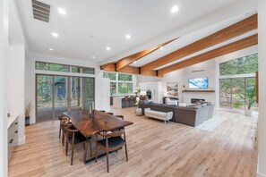 A modern interior with a dining area, kitchen, and living space, featuring large windows and wooden beams. - Luxury Mountain Getaway Minutes from Crystal Mountain & Mount Rainier (Enumclaw)