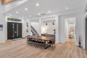 Ein geräumiger Essbereich mit Holztisch und -stühlen, einer Treppe und einer Küche mit moderner Einrichtung.
