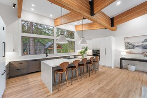 A modern kitchen with a central island, wooden chairs, and large windows. - Luxury Mountain Getaway Minutes from Crystal Mountain & Mount Rainier (Enumclaw)