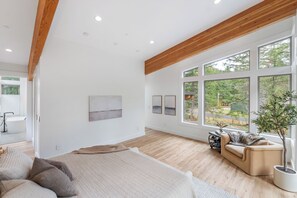 Ein geräumiges Zimmer mit großem Fenster, Holzbalkendecke und einem Bett mit Kissen.