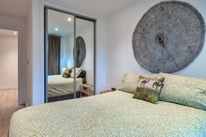 A bedroom with a large bed, a mirror, and a wall art piece. - Stylish City Apartment With Terrace (Plymouth)