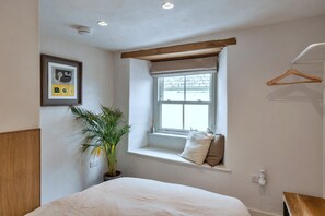 A bedroom with a bed, a window with a view, a plant, and a framed picture on the wall. - Kingsand Coastal Retreat for 6 (Torpoint)